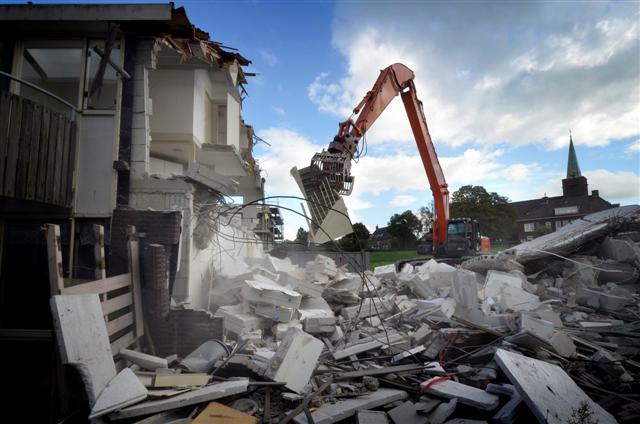 NIEUWKOOP - In Nieuwkoop sloopt een eenzame medewerker van Spelt uit Nieuwveen een oud blok woningen dat plaats gaat maken voor de laatste fase van nieuwbouwproject Klipperaak. Terwijl links al een deel van de door bouwbedrijf Vink+Veenman gebouwde woningen bewoond zijn, wordt rechts een nieuw blok binnenkort opgeleverd. In opdracht van Woning Stichting Nieuwkoop  moeten uiteindelijk vijf vijf bouwblokken verrijzen die ruimte gaan bieden aan 58 levensloopbestendige appartementen voor senioren. Terwijl vroeger de woningen grotendeels met de hand gesloopt werden, trekt de machinist tegenwoordig met uiterste precisie de woningen open en scheidt hij direct het sloopafval op ondermeer metalen, steen en houten zoldertrap. COPYRIGHT TON BORSBOOM