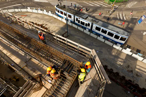 Nederland, Amsterdam, 27 maart 2012.
Aanleg Noord-Zuidlijn van de Amsterdamse Metro.
Het werkterrein aan de Prins Hendrikkade, ter hoogte van Brug 303.
Op het werkterrein aan de Prins Hendrikkade wordt het laatste caisson van de Noord/Zuidlijn gebouwd.
Het caisson steunt op ‘snijranden’, twee meter hoge randen aan de onderzijde ervan. Ze zorgen ervoor dat
het caisson straks makkelijk de grond in zakt.
Nu wordt op het dak van het caisson een twaalf meter hoge schacht gebouwd.
Tijdens het afzinken van het caisson, dat volgens de huidige planning in mei begint,
wordt al het benodigde materiaal via deze schacht aangevoerd. De bouw van de schacht
duurt een maand.
The City of Amsterdam is building a new subway (underground) line.
The tunnel is partly constructed underneath the old part of the city.
The completion of the metro line is scheduled for 2017.
Foto: Ge Dubbelman/Hollandse Hoogte.
Opdrachtnummer: D10023
