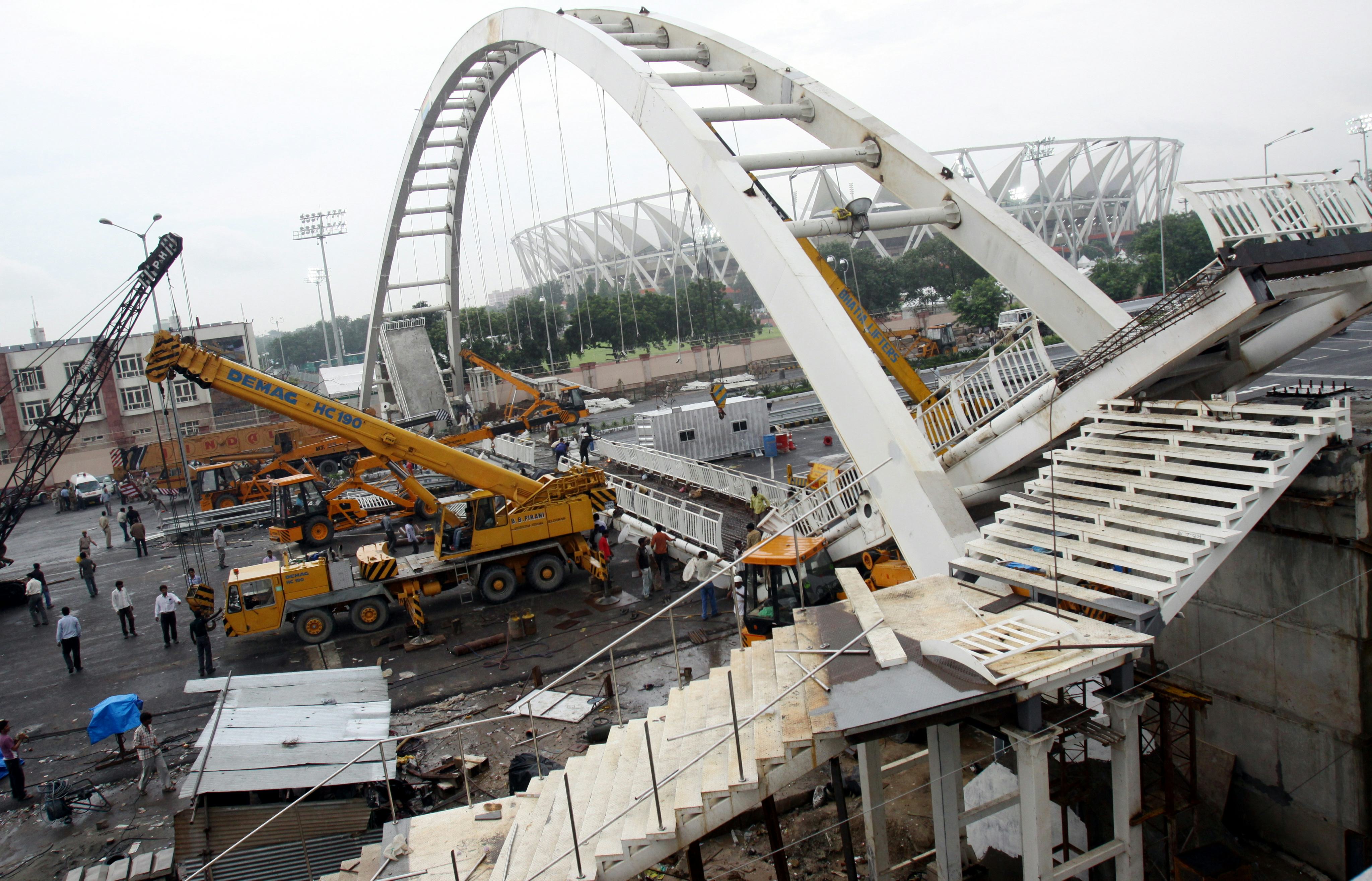 epa02349764 Construction workers work to remove debris from a footover bridge that collapsed near Jahawarlal Nehru Stadium in New Delhi, India on 21 September 2010. According to media reports 23 people are reported to be injured. The Commonwealth Games Delhi 2010 are scheduled to be held in Indian capital New Delhi from 03 October to 14 October 2010. EPA/ANINDITO MUKHERJEE