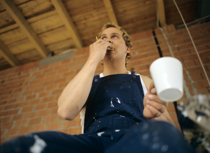 Man eating, holding coffee mug, low angle view