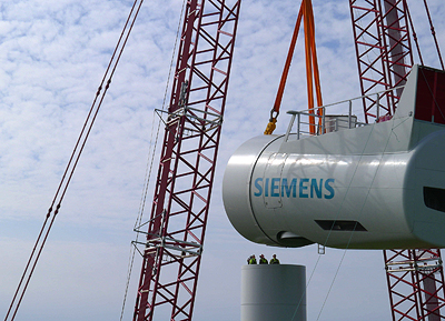 Die Gondel des Prototyps wird auf den Turm gehoben. Dieser erste Prototyp wird jetzt umfangreichen Test hinsichtlich Leistungsfähigkeit und Verfügbarkeit unterzogen. 

The nacelle of the prototype is lifted to the top of the tower. Siemens is in the process of thoroughly testing and validating the performance of the new wind turbine before the product will be officially launched for sale in the near future.