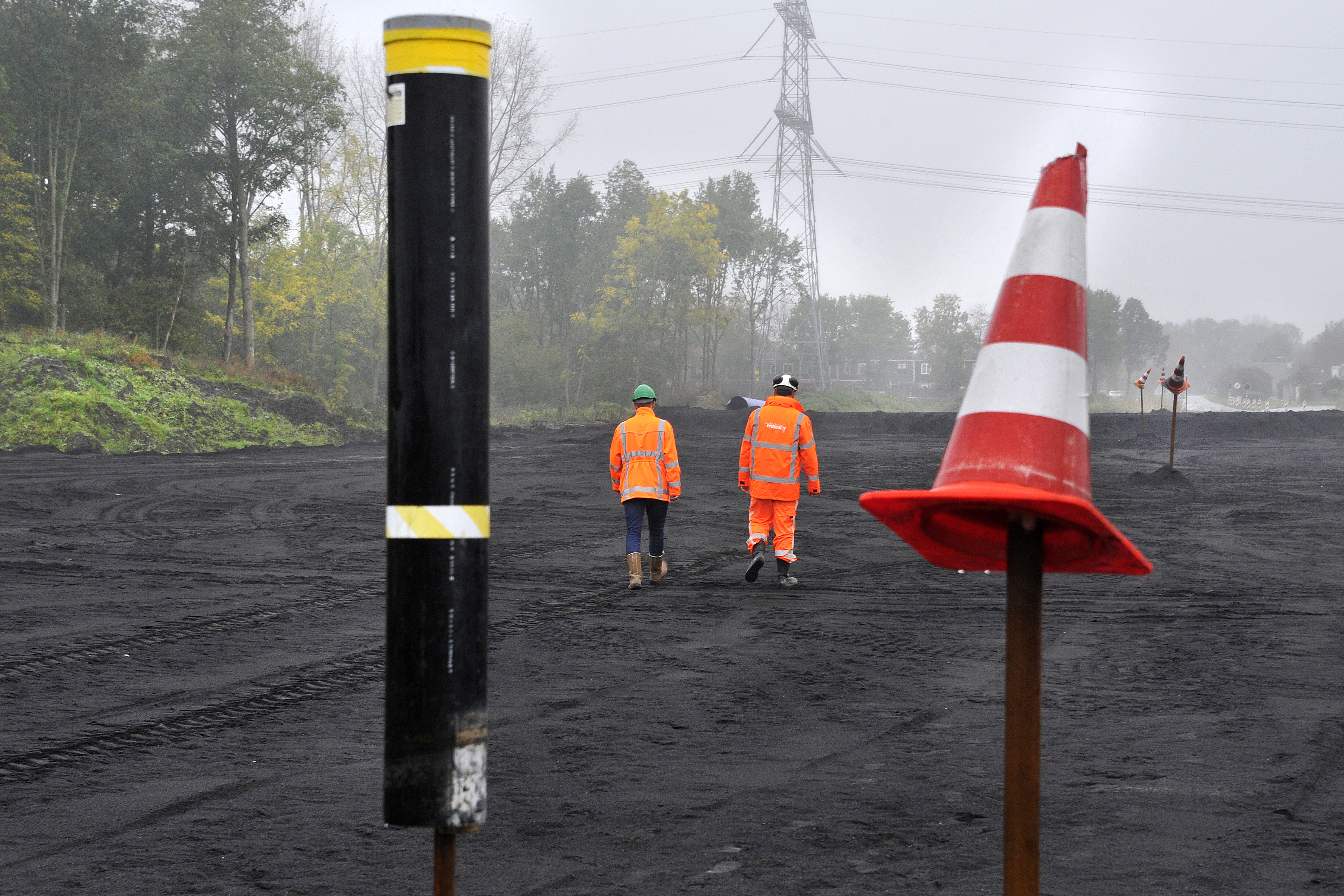 Ecozand op een van de lokale wegen langs de A6 bij Almere. De stokken met oranje pionnen zijn ‘zakbakens’, waarmee gemeten kan worden hoeveel de zandlaag zakt. De pionnen boven op de bakens zijn voor de zichtbaarheid, vooral om aanrijdingen te voorkomen.