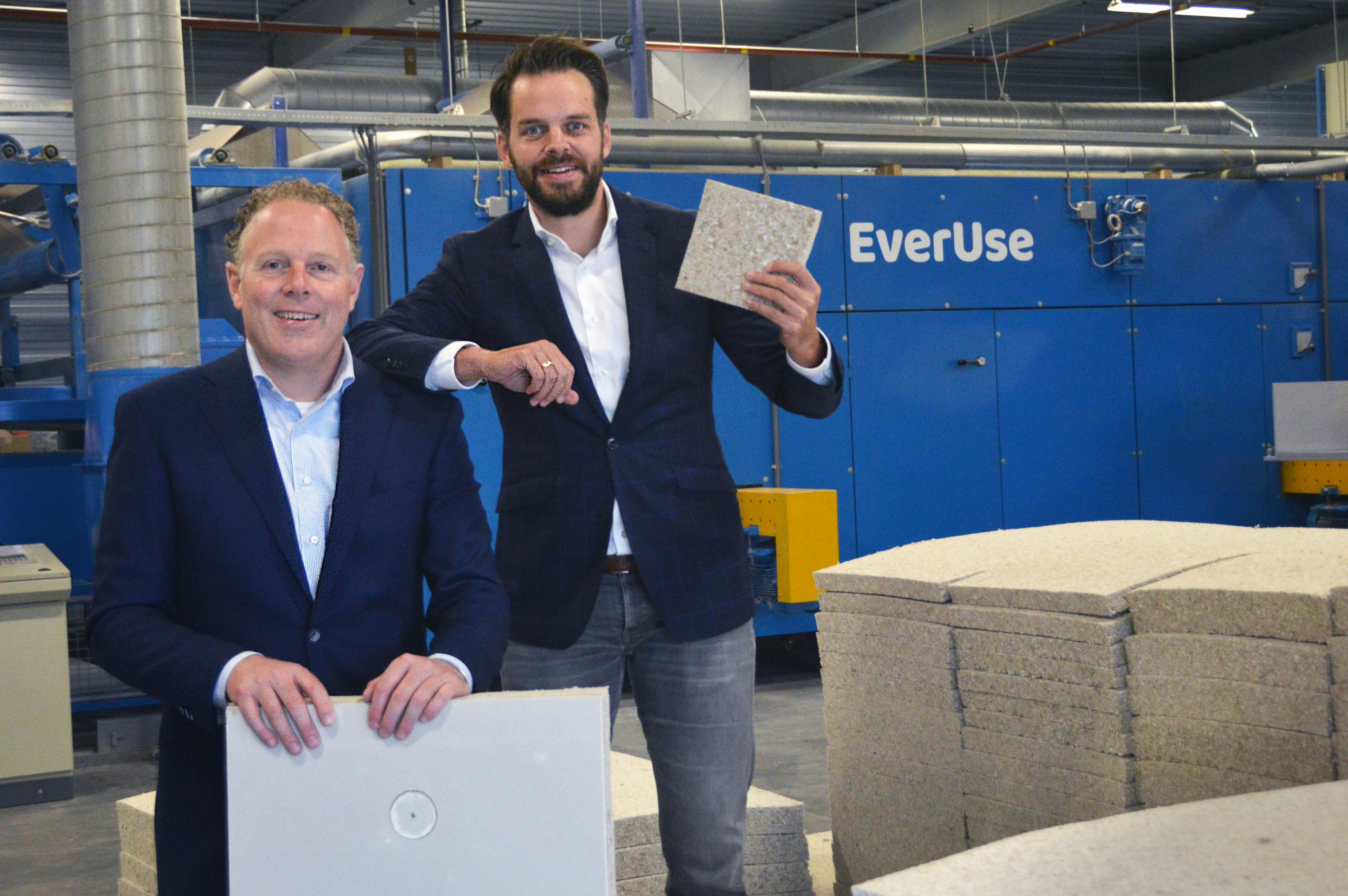 Everuse directeuren Marc van der Heijden (links) en Martijn Vinke gefotografeerd bij hun eindproduct: isolatiemateriaal van karton en papier. Op de achtergrond de machine die het materiaal maakt.