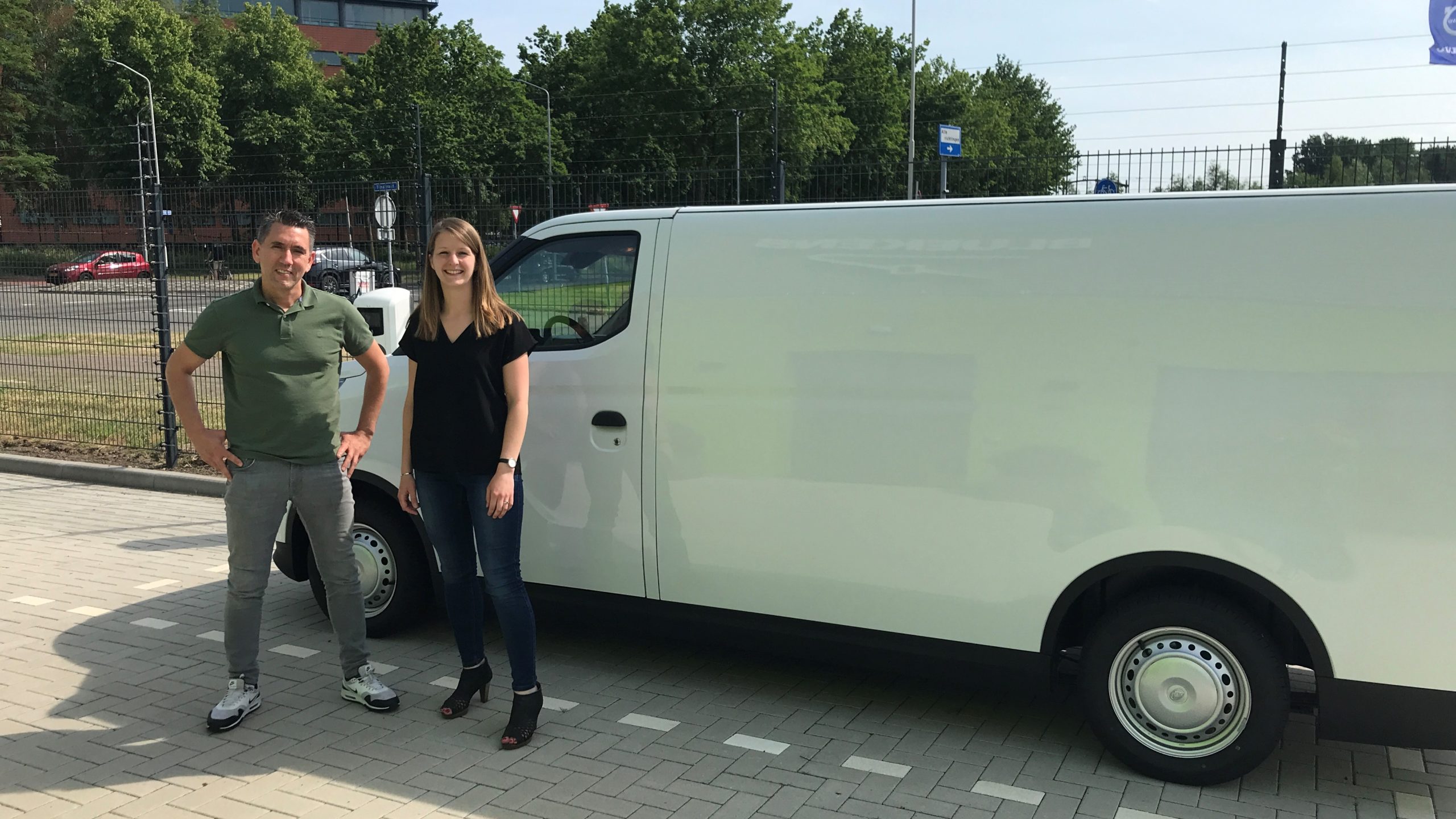 Thomas van Belzen (Cobouw) en Karin Vermeulen (Bluekens EV) voor de elektrische bus waarmee Thomas deze zomer door het land toert. De bus wordt nog voorzien van het kersverse Fixers-logo. Foto: Cobouw 