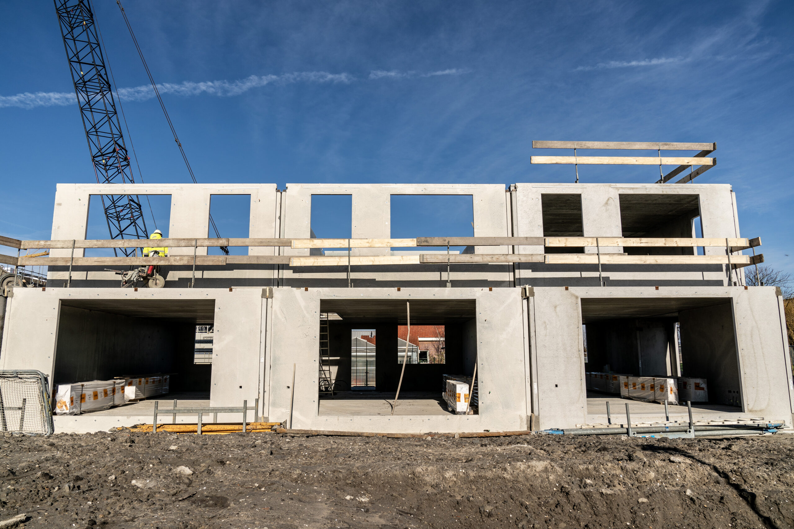 Je ziet het er niet aan af, maar twee van dit rijtje van vier woningen in aanbouw in 's Gravenzande zijn door Heembeton en Heijmans gerealiseerd met wanden en gevelementen van geopolymeerbeton. Foto: Heembeton