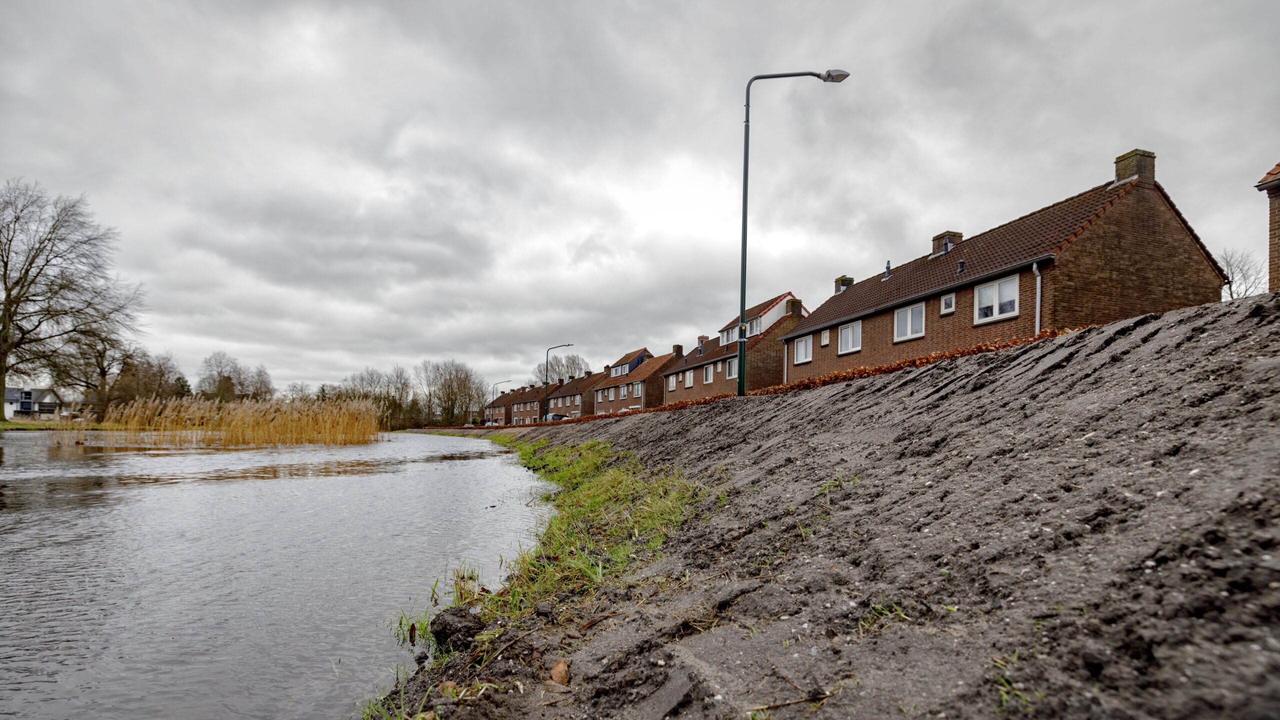 Waterschap De Dommel legde een dijk van zand aan om huizen te beschermen tegen hoogwater na veel regen. Foto: ANP/Hollandse Hoogte/Dolph Cantrijn