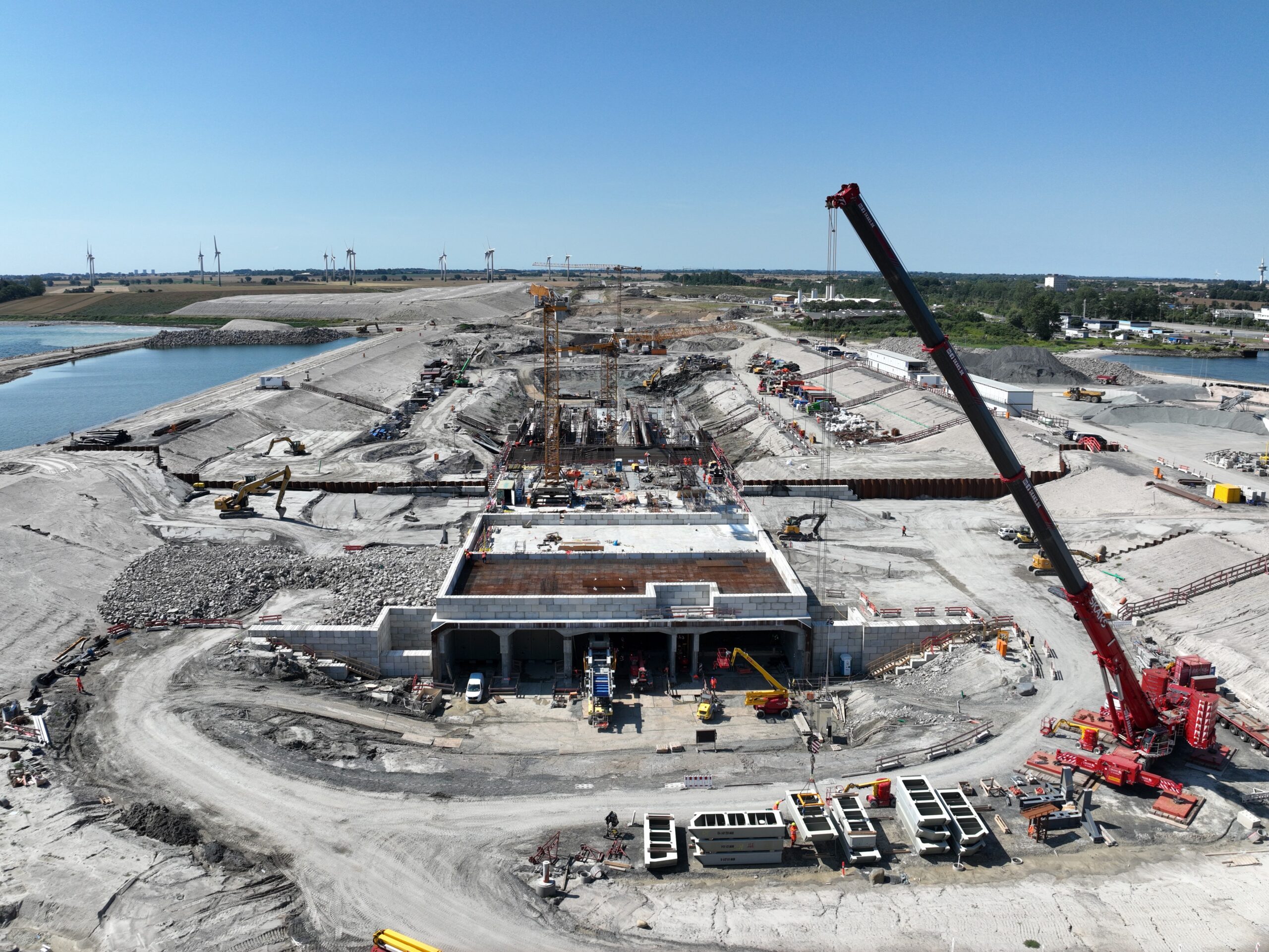 De tunneltoerit aan de Duitse kant bij Puttgarden. Inmiddels is er een kopschot geplaatst in de betonconstructie en is de bouwput onder water gezet door de dijk aan de noordkant weg te baggeren. Foto: Femern A/S