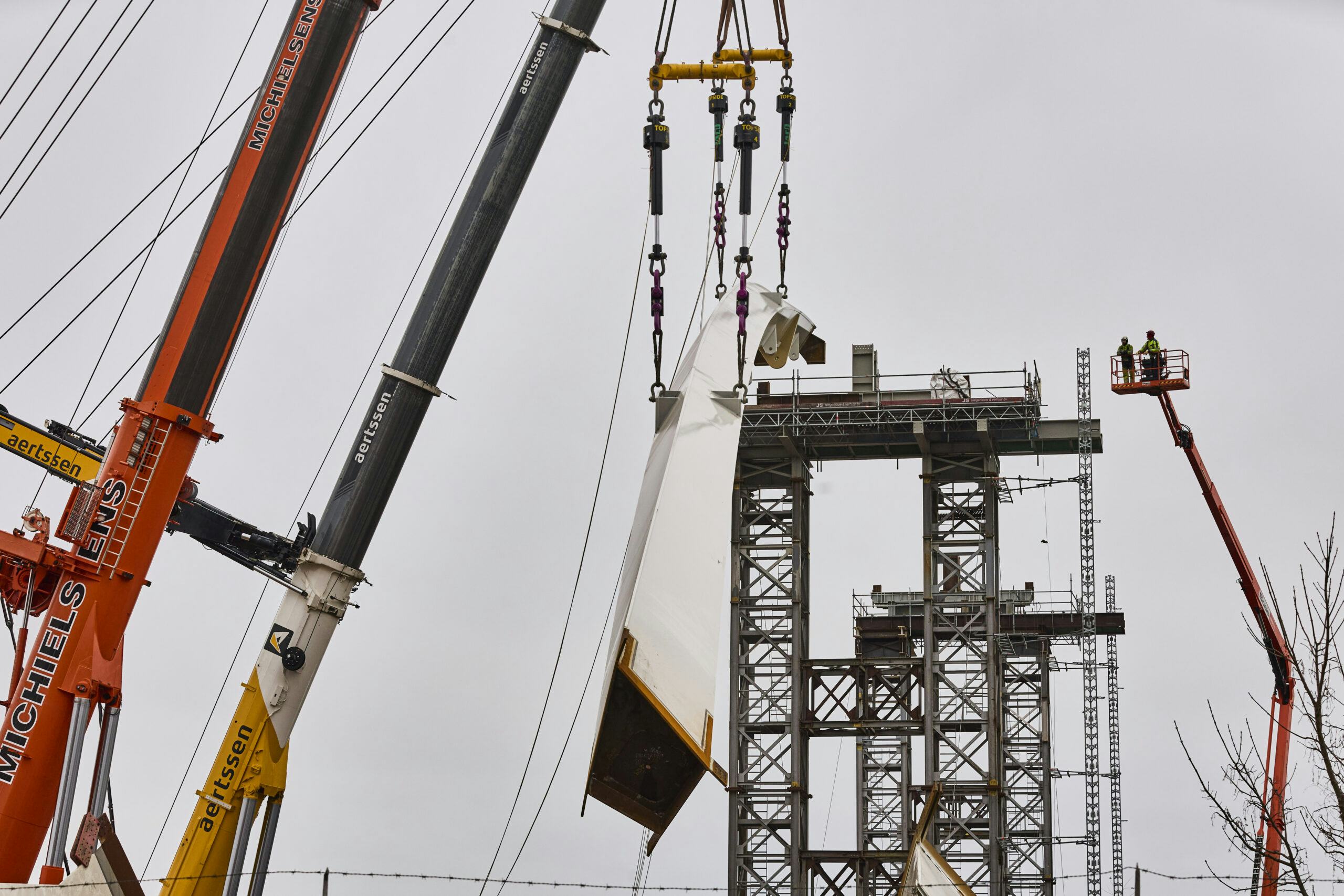 Dinsdag is het eerste boogdeel voor de Nettelhorsterbrug op zijn plek gelegd. Bij de vier hijspunten zijn de synclifts zichtbaar waarmee de 140 ton zware ligger heel minutieus op zijn plek kan worden gelegd.  Foto: Arjan Gotink