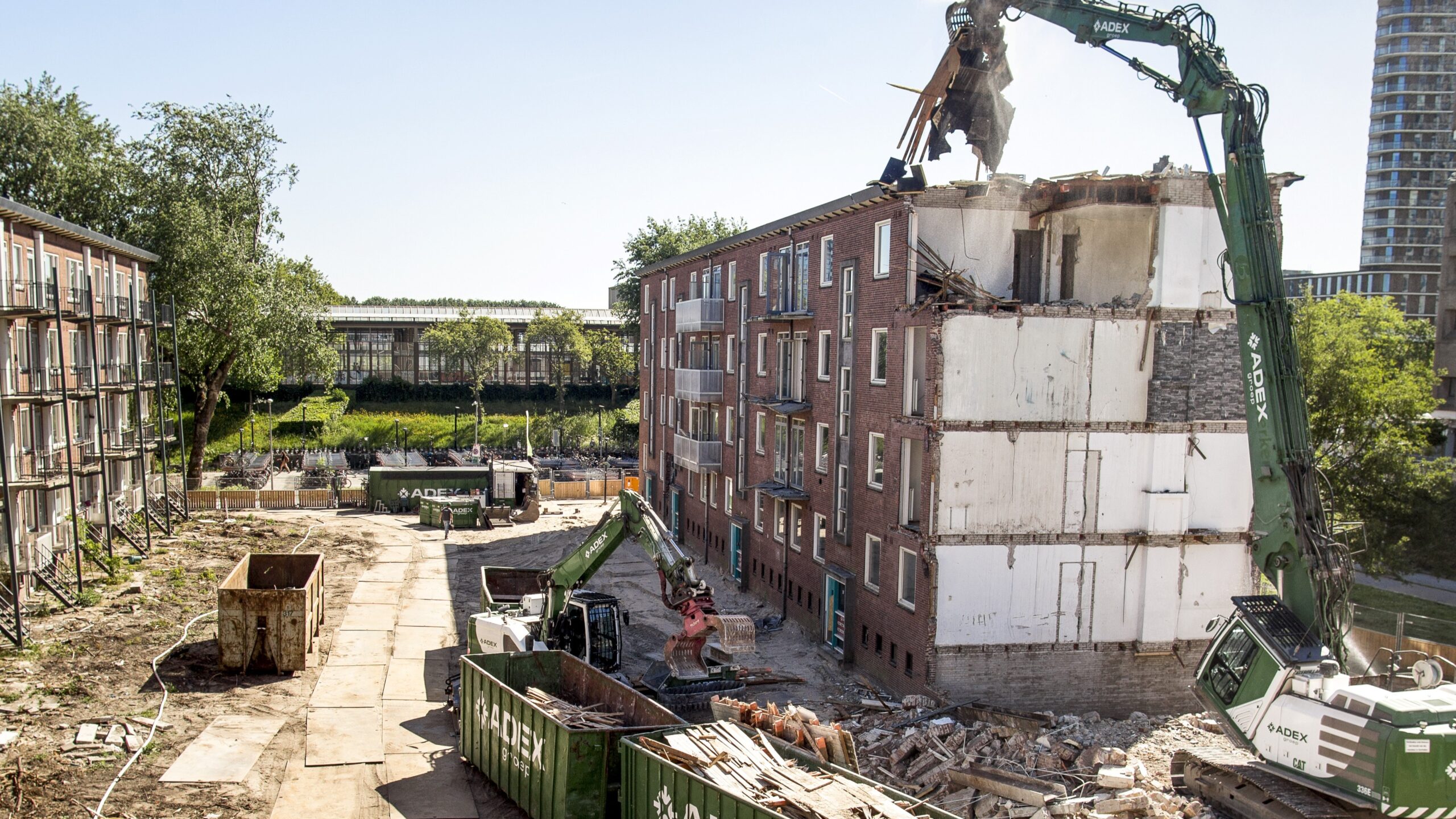 In de Amsterdamse Van der Kunbuurt worden oude portiekflats gesloopt om plaats te maken voor nieuwe appartementen. Op de grond staan afvalcontainers voor houtafval. Foto: Eran Oppenheimer