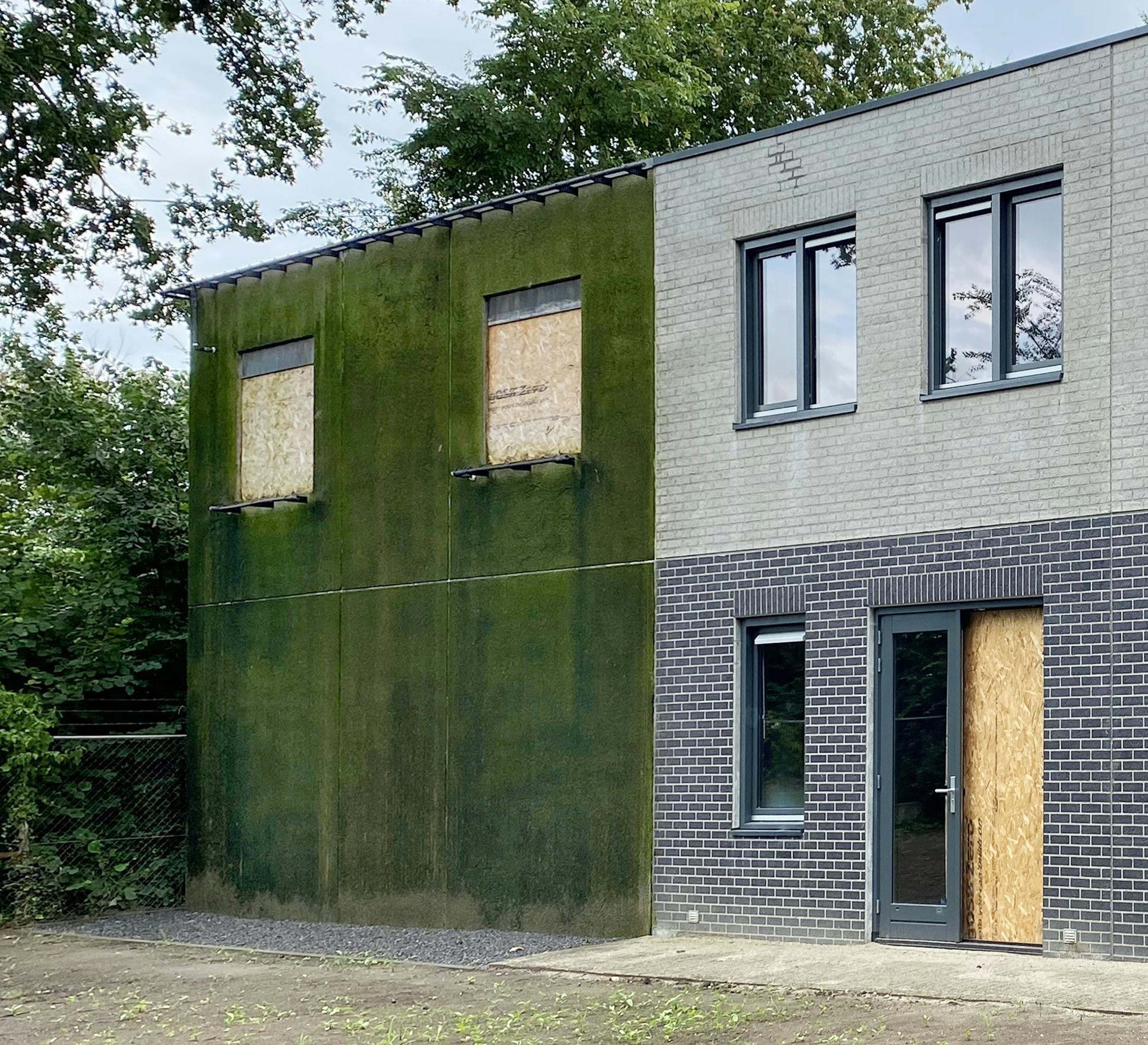 De nieuwe bedrijfshal krijgt een unieke uitstraling. Hebben de Bloqz-woningen (rechts) nog enkel een traditioneel baksteenmotief, bij de hal wordt dat een combinatie van glad beton, baksteenmotief en als bijzonderheid: mos (links op de foto), omdat dit een duurzame wand oplevert, die CO2 opneemt en zuurstof uitstoot.