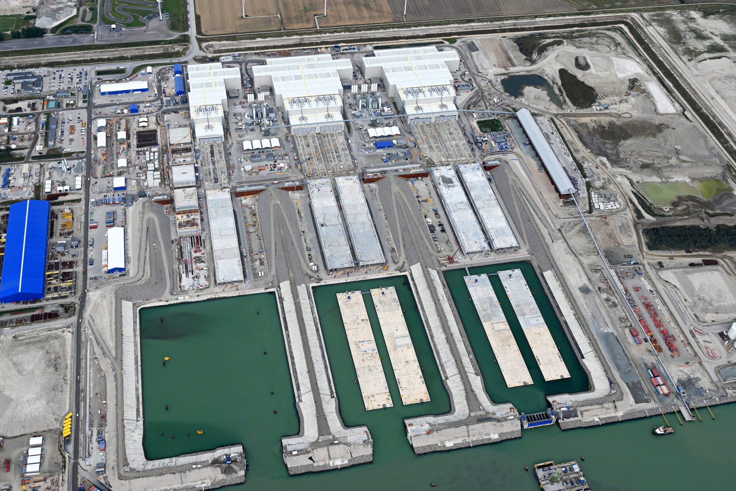 Voor de tunnelfabriek in Rodbyhavn hopen de kant en klare tunnelelementen zich inmiddels op. Slechts twee van de productielijnen is nog actief en draait op minder dan halve kracht. Foto: Femern A/S 