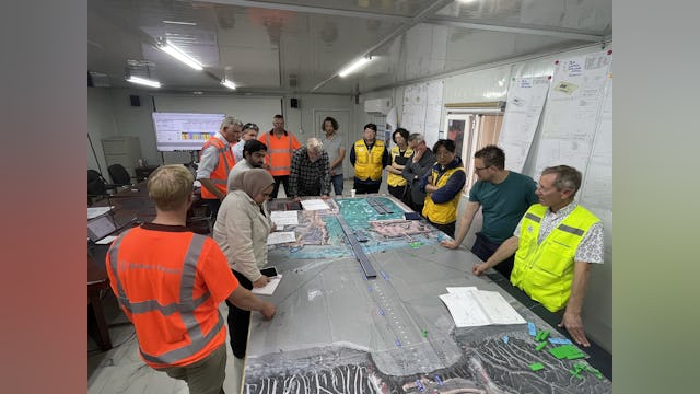 Om ieders rol tijdens een afzinkoperatie vooraf scherp te krijgen werd dat droog geoefend met modelletjes van de elementen op een uitvergrote satellietfoto van de bouwplaats en de rivier. Foto: Ballast Nedam