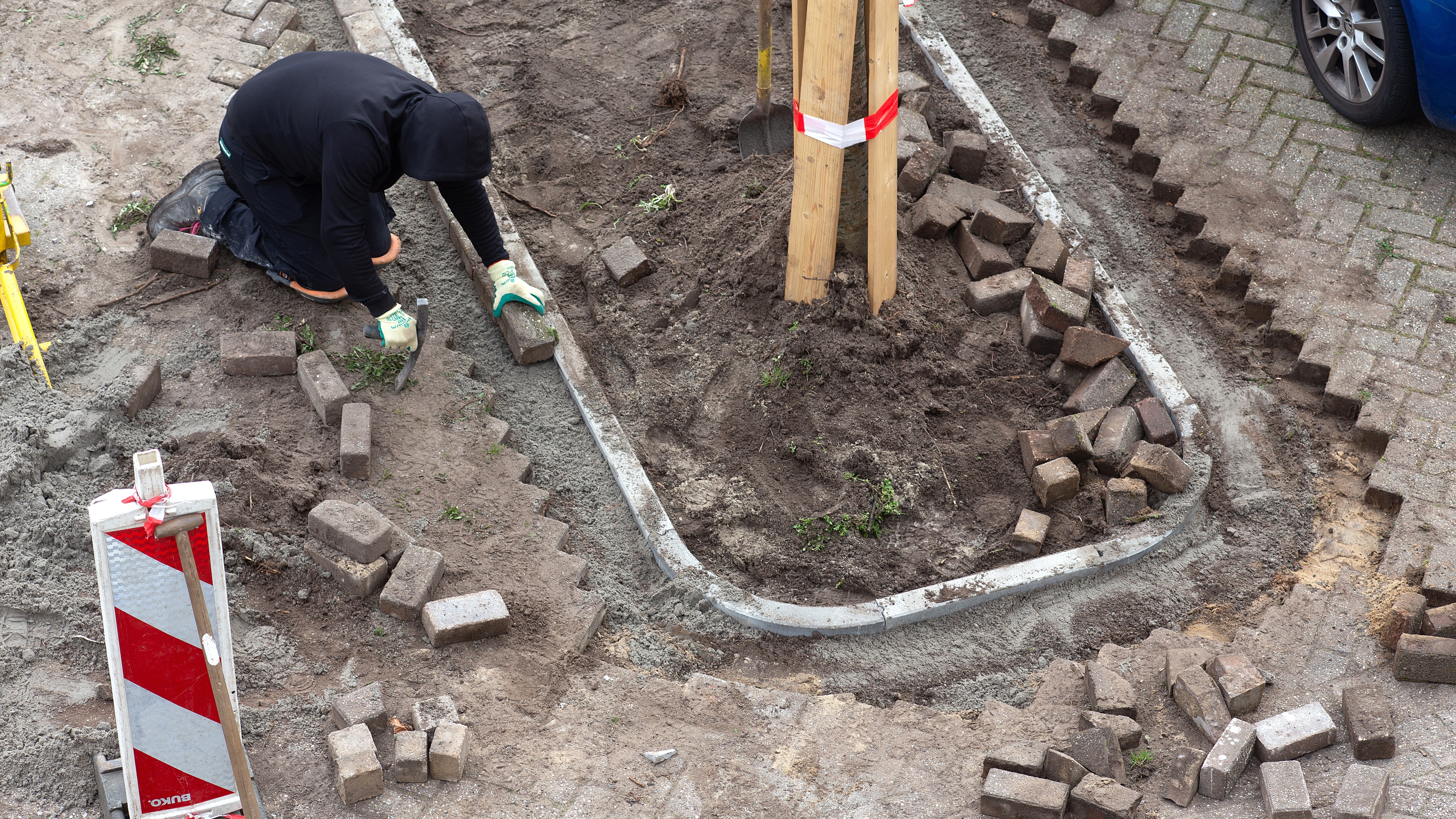 In de wijk Hoep Zuid  in Schagen zijn stratenmakers  aan het werk om parkeerplekken en klinkers te vervangen  door perken met groen. Foto: ANP