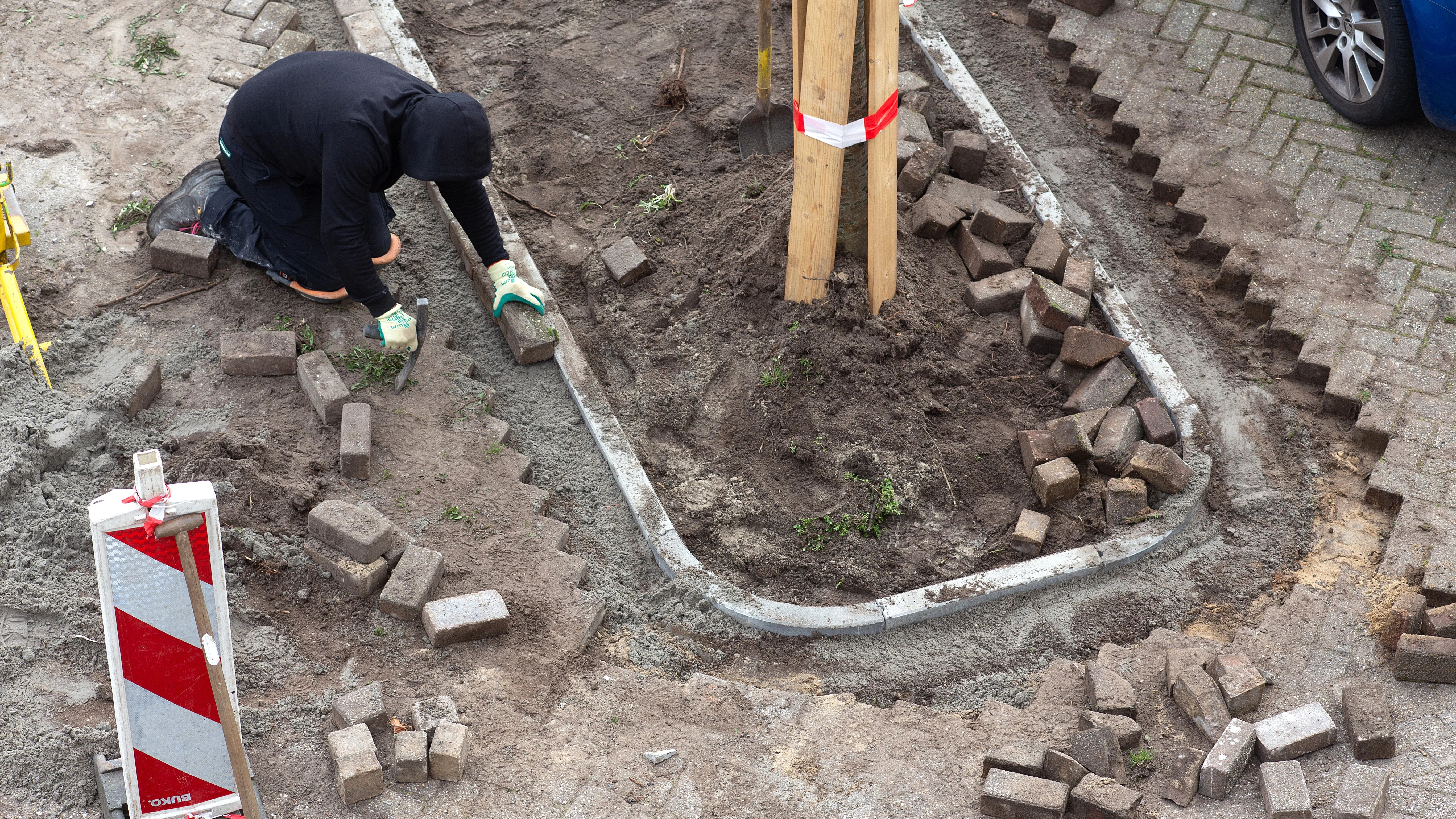 In de wijk Hoep Zuid in Schagen zijn stratenmakers aan het werk om parkeerplekken en klinkers te vervangen door perken met groen. Foto: ANP