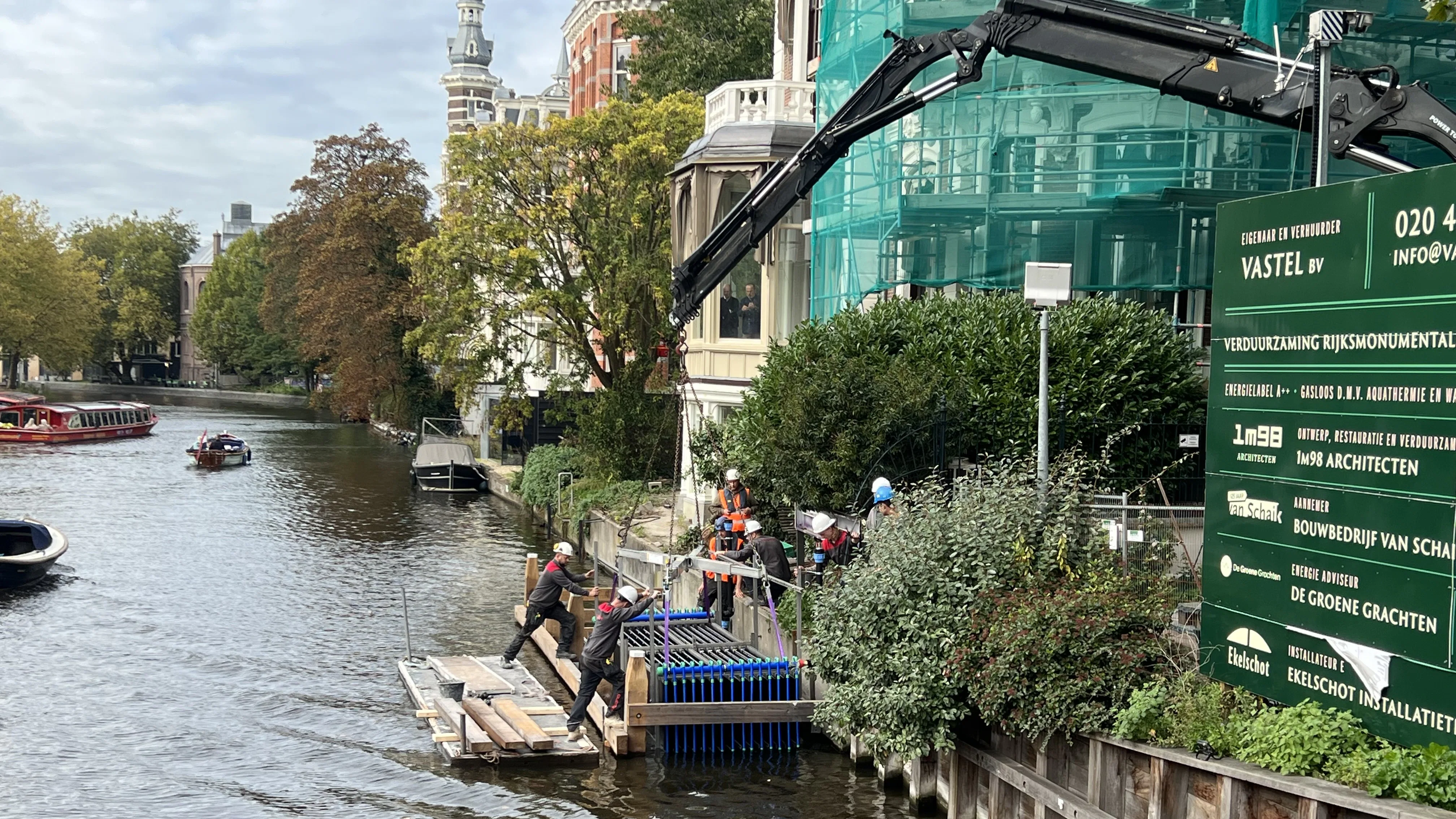 Een kraan liet de 1,5 meter brede rij aquathermiepanelen donderdagmiddag voorzichtig in de Singelgracht zakken. Foto: Cobouw